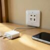 Prise japon murale à deux fentes plates dans une chambre d'hôtel, avec un chargeur européen et un téléphone posés sur le bureau