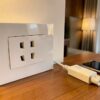 Prise chine murale blanche dans une chambre d'hôtel, avec un chargeur et un smartphone posés sur le bureau face à la ville
