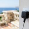Prise Chypre : adaptateur de voyage branché sur une prise murale anglaise, balcon et mer Méditerranée en arrière-plan