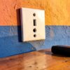Prise Colombie illustrée sur un mur peint de couleurs vives, chargeur de téléphone posé sur une table en bois