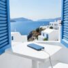 Prise Grèce : téléphone en charge sur une table blanche d'un balcon d'hôtel dans les îles grecques, volets bleus et mer Égée