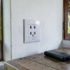 Prise Sri Lanka sur le mur blanc d'une maison d'hôtes ouverte sur un jardin tropical, batterie externe posée sur une table en bois