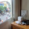 Prise Vietnam dans une chambre d'hôtel de Hanoï, adaptateur de voyage, chargeur et téléphone posés sur la table de chevet