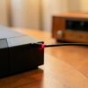 Sortie optique TV : câble optique à la lumière rouge branché à l'arrière d'une télévision, chaîne hifi en bois en arrière-plan